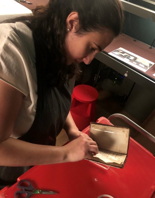 A conservator with a book, book cradle and associated materials