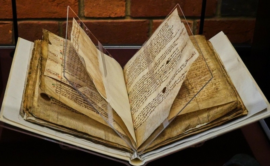 A medieval manuscript on display with pages supported on perspex